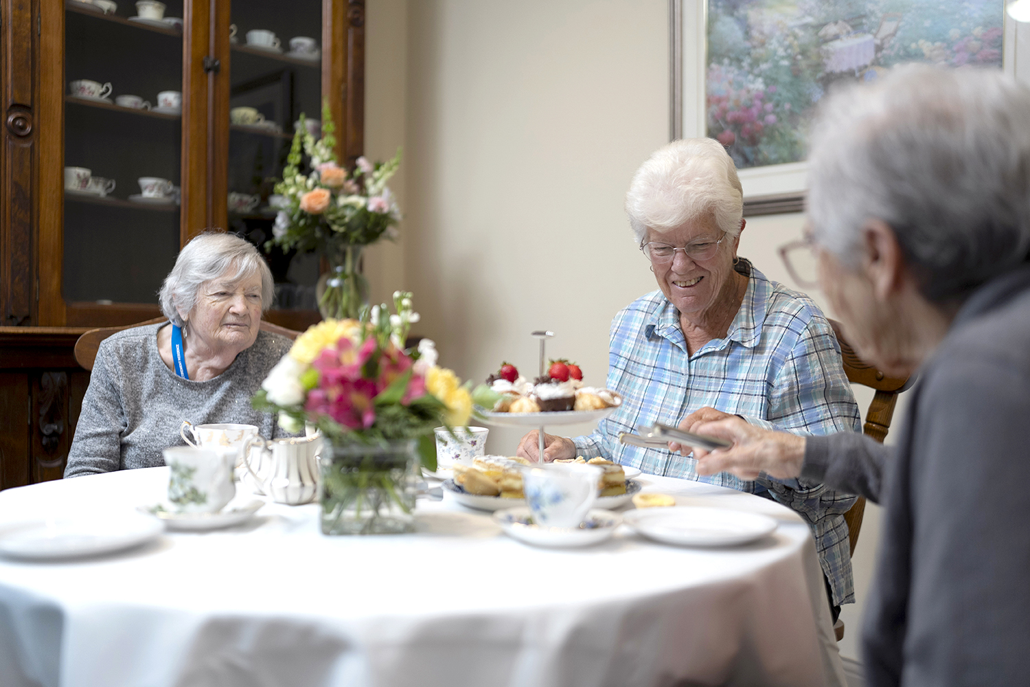 Residents enjoying afternoon tea with a tray of cakes and treats at Atrium retirement residence